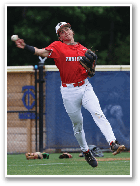 A baseball player in a red shirt and white pants is leaping into the air to catch a ball. AI generated content