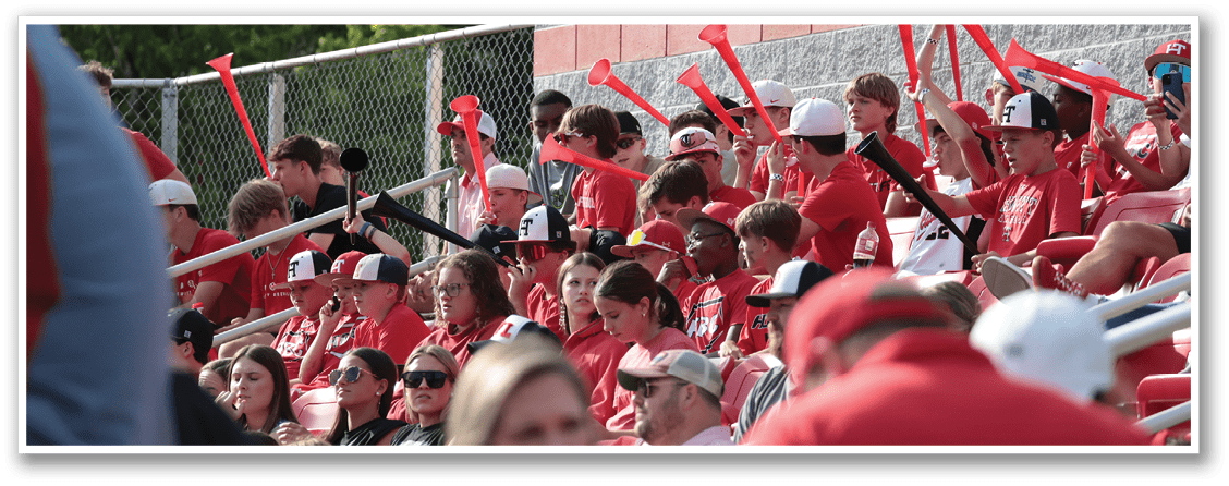 A group of people are sitting in the stands at a baseball game. They are holding red and white toy instruments, possibly toy guitars, and are waving them in the air. AI generated content