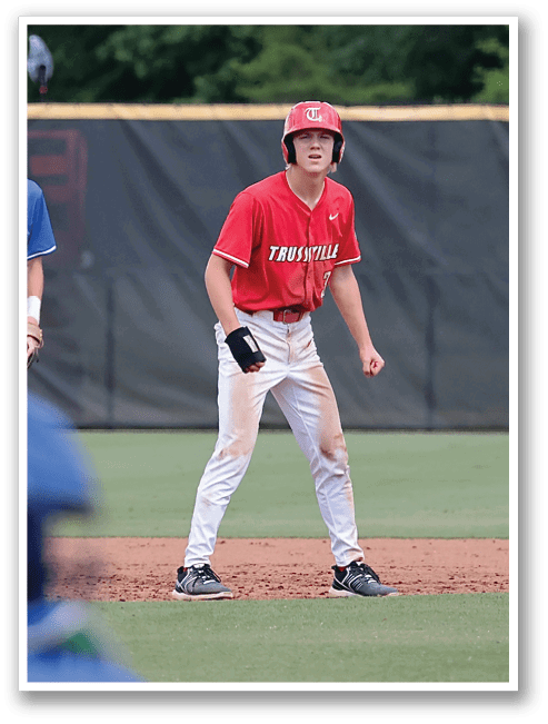 A baseball game is in progress with a player in a red shirt and white pants running to the first base. The player is wearing a helmet for protection. The catcher is ready to throw the ball to the first baseman. AI generated content