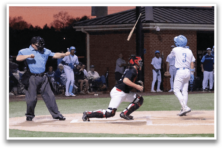 A baseball game is in progress with a batter swinging at a pitch. The umpire is standing behind the batter, ready to make a call. The catcher is positioned behind the batter, wearing a baseball glove. Several other players are on the field, some of them holding baseball bats. The scene is set in a stadium, with a crowd of spectators watching the game. AI generated content