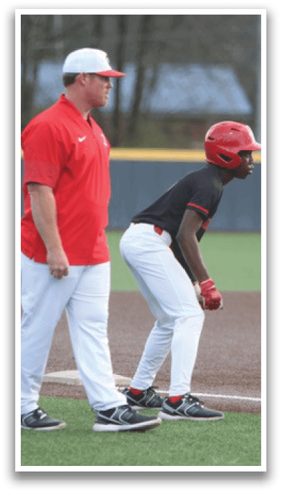 A baseball player is standing on the field, wearing a red helmet and white pants. A coach is standing behind him, watching the game. Another player is standing in the background, wearing a baseball glove. AI generated content