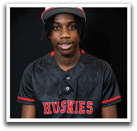 A young man wearing a black baseball jersey with the number 10 on it is sitting on a stool. AI generated content