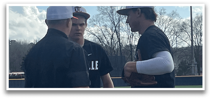 Two baseball players wearing black shirts and white pants are talking to each other on a field. AI generated content