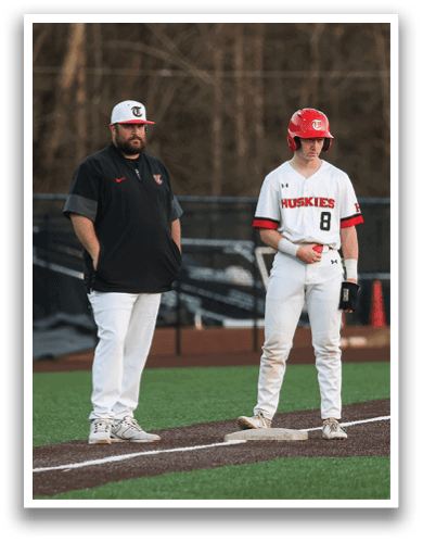 Two men are standing on a baseball field, one of them wearing a red helmet. AI generated content