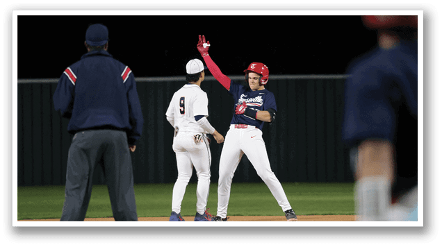 Three baseball players are on a field, with one player holding his arms up in the air. The other two players are standing nearby, one of them wearing a red helmet. The scene appears to be taking place during a game. AI generated content