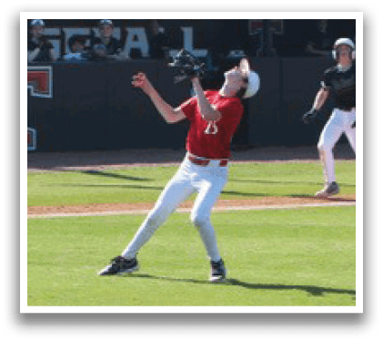 A baseball game is in progress with a player throwing a ball to another player. There are several other players on the field, some of them wearing baseball gloves. The scene takes place in a field with a building in the background. AI generated content