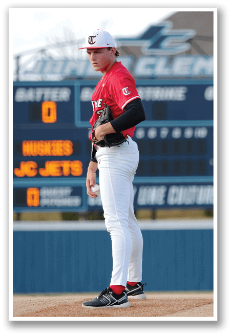 A baseball player in a red jersey stands on the pitcher's mound, holding a baseball glove. AI generated content