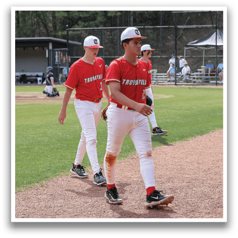 Two baseball players wearing red uniforms walk on the field. AI generated content