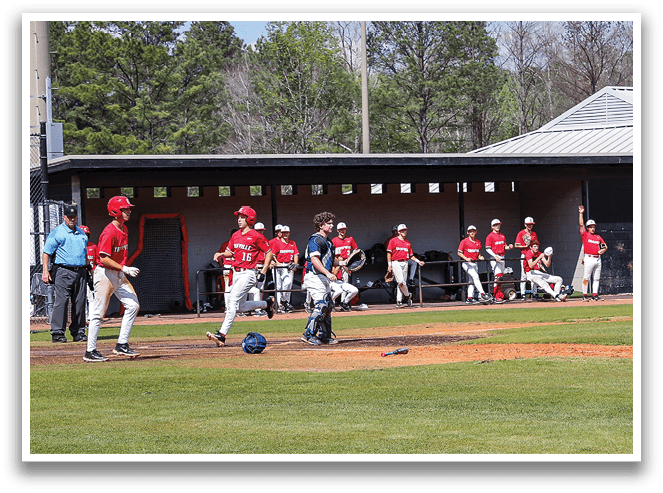 A baseball game is in progress with a group of men on the field. One player is holding a baseball bat, ready to swing. There are several other players in various positions on the field, some holding baseball gloves. A sports ball is visible in the scene. The players are wearing baseball uniforms, and the atmosphere is lively as they engage in the game. AI generated content