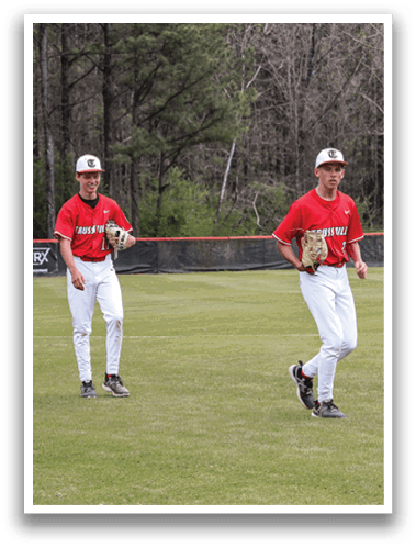 Two baseball players are walking on a field, one wearing a red shirt and the other wearing a red and white shirt. They are carrying baseball gloves. AI generated content