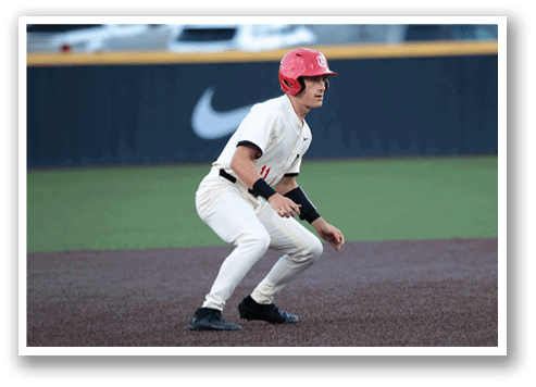 A baseball player in a red helmet and white uniform is crouching on the field. AI generated content