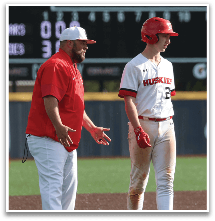 Two men on a baseball field, one wearing a red shirt and the other wearing a white shirt. The man in the red shirt is talking to the man in the white shirt. AI generated content