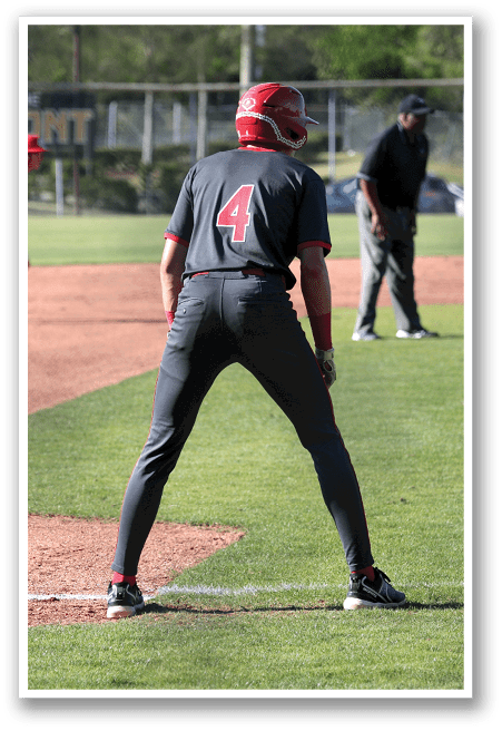 A baseball player is standing on the field, wearing a black shirt and red hat. He is holding a baseball bat and is ready to hit the ball. There are two other players on the field, one of them is wearing a baseball glove. The scene takes place in a baseball field with a car parked in the background. AI generated content