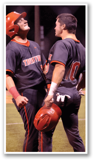 Two baseball players wearing black jerseys and red helmets are talking to each other on the field. AI generated content