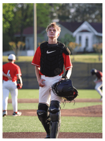 A baseball player wearing a red shirt and black helmet stands on the field. AI generated content