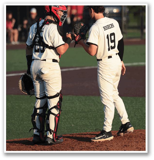 Two baseball players are standing on the field, talking to each other. One player is wearing a red helmet. AI generated content