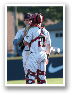 Two baseball players wearing red and white uniforms are standing on a field, talking to each other. AI generated content