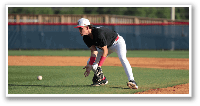 A baseball player in a black shirt and white pants is bending over to catch a ball. AI generated content