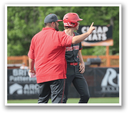 Two men are standing on a baseball field, engaged in conversation. One man is pointing, while the other is wearing a red shirt. AI generated content
