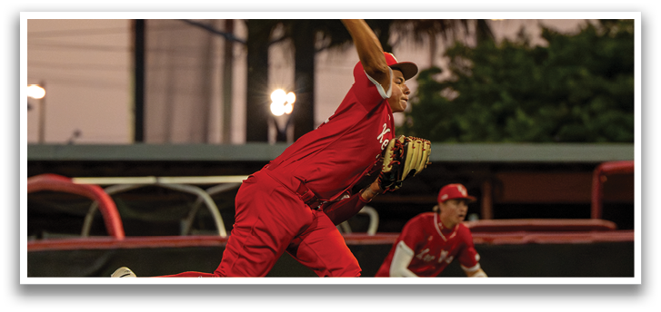 A baseball player in a red shirt and red pants is throwing a ball. Description generated by AI