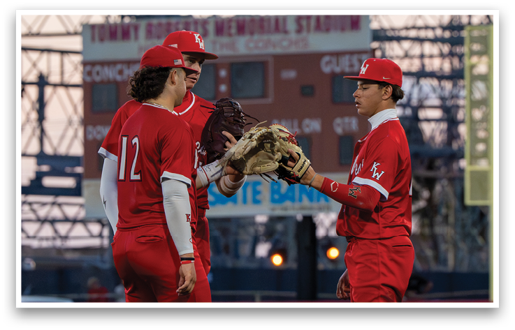 Two baseball players wearing red uniforms and white hats. Description generated by AI
