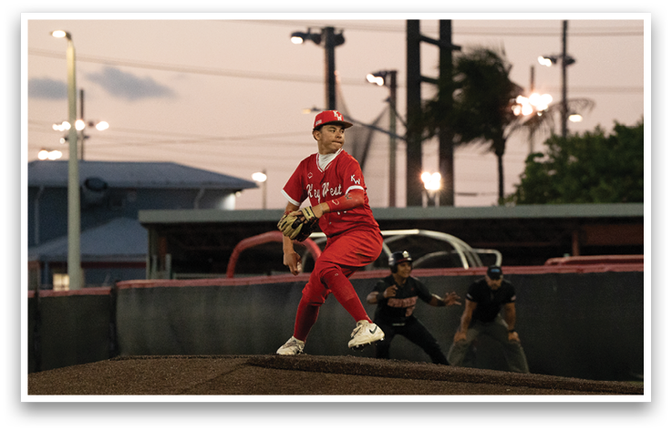 A baseball player in a red shirt and red pants is pitching a ball. Description generated by AI
