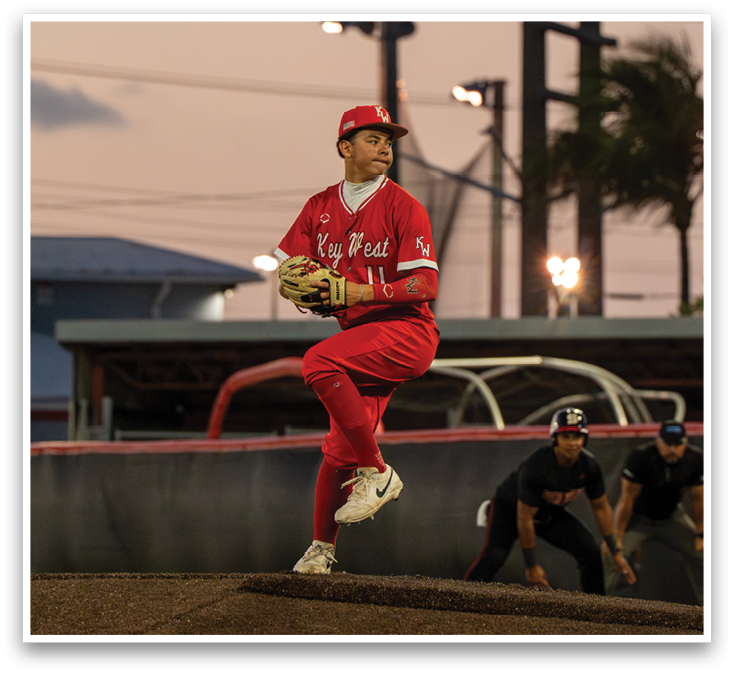 A baseball player in a red jersey and white pants is in the process of throwing a ball. Description generated by AI