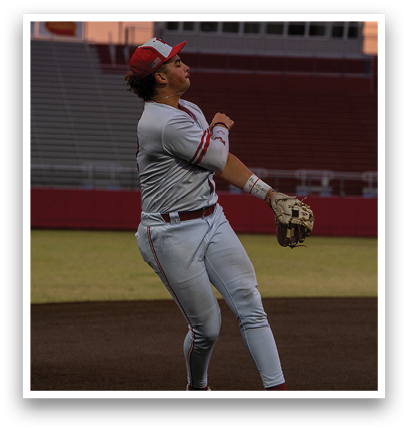 A baseball player wearing a red hat and white uniform is jumping in the air to catch a ball. Description generated by AI