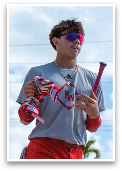 A man wearing a grey shirt and red shorts holding a baseball bat. Description generated by AI