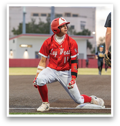 A baseball player wearing a red jersey with the number 11 kneeling on the ground. Description generated by AI