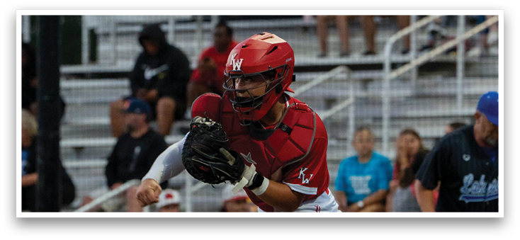 A baseball player wearing a red shirt and white pants is holding a baseball mitt. Description generated by AI