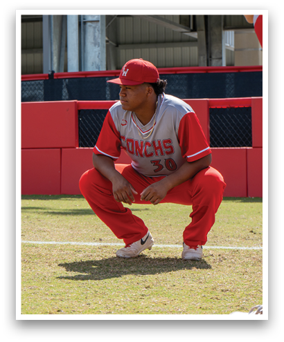 A baseball player wearing a red jersey and red pants is crouching on the field. Description generated by AI
