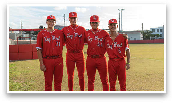 Four young men wearing red baseball uniforms. Description generated by AI