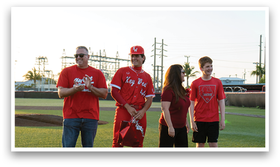 Three people standing on a baseball field. Description generated by AI