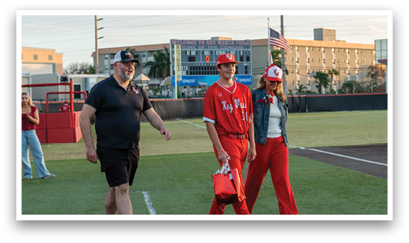 A man and woman walking on a baseball field. Description generated by AI
