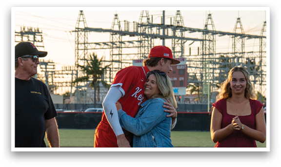 A man and a woman hugging on a baseball field. Description generated by AI