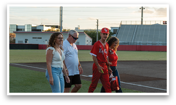 A group of people walking on a baseball field. Description generated by AI