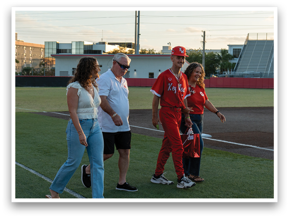 A group of people walking on a baseball field. Description generated by AI
