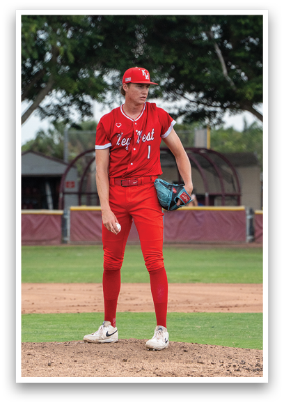 A baseball player in a red jersey and red pants is standing on a mound. Description generated by AI