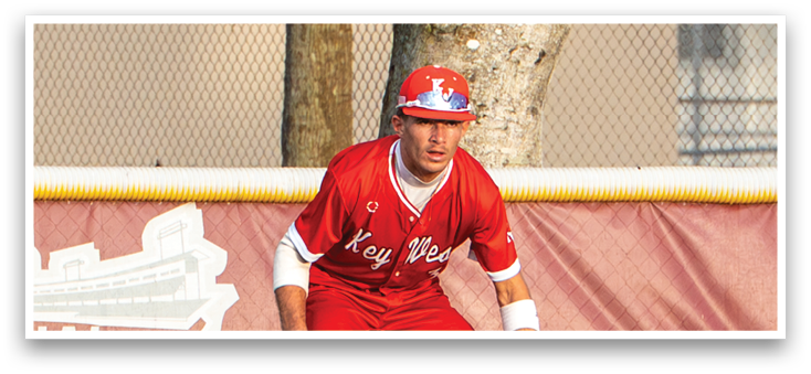 A baseball player in a red uniform is crouching on the field. Description generated by AI