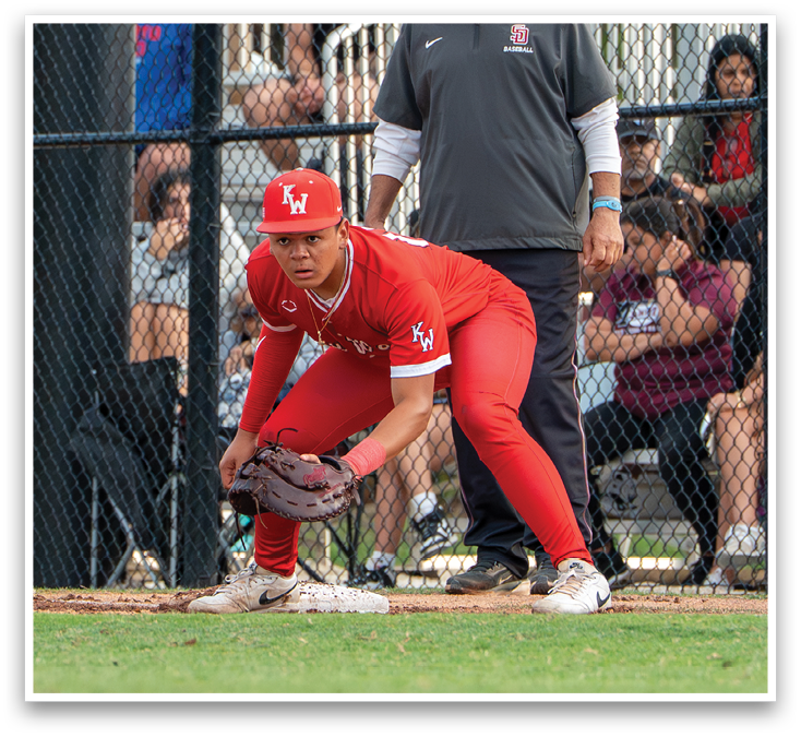 A baseball player is kneeling on the field wearing a red shirt and red pants. Description generated by AI