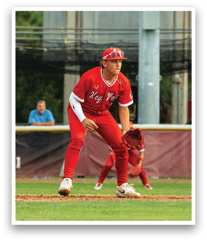 A baseball player in a red uniform is standing on the field. Description generated by AI
