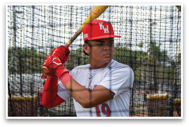 A baseball player wearing a red and white uniform and holding a bat. Description generated by AI