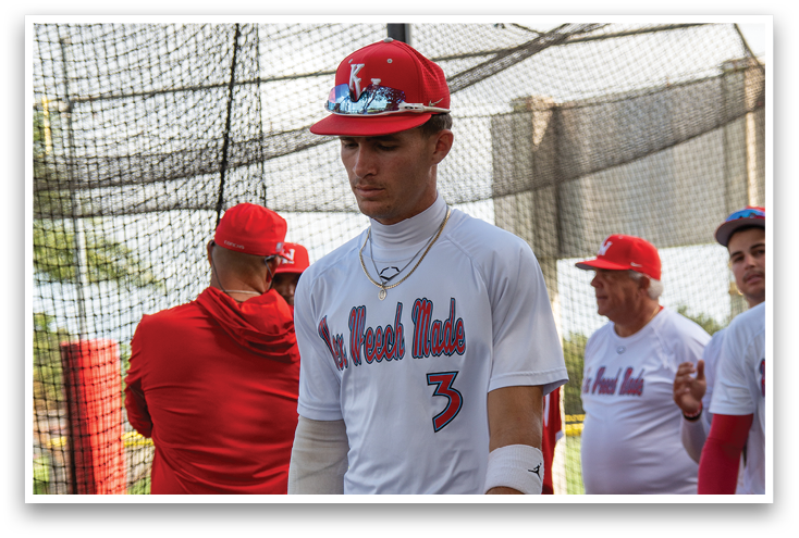 A man wearing a red baseball uniform with a bat in his hand. Description generated by AI