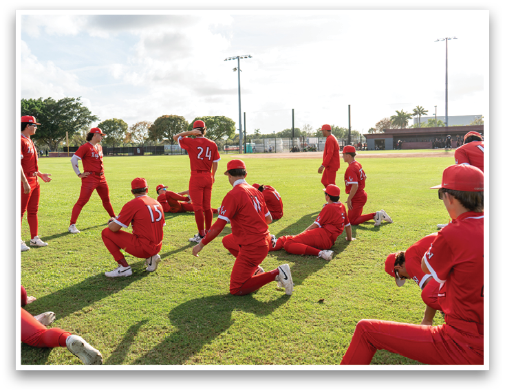 A group of people wearing red and white uniforms are sitting on the grass. Description generated by AI