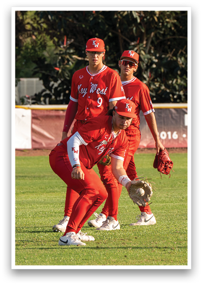 Three men wearing red shirts and red pants are standing on a baseball field. Description generated by AI