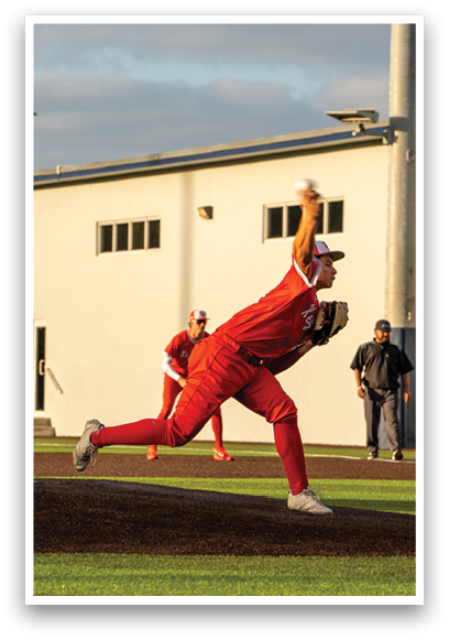 A baseball player in a red shirt and red pants is throwing a ball. Description generated by AI