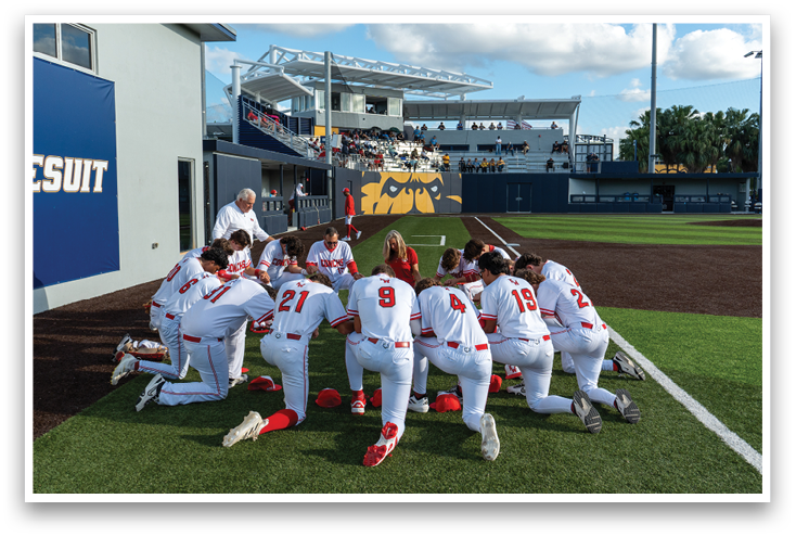 Baseball players in red and white uniforms praying on the field. Description generated by AI