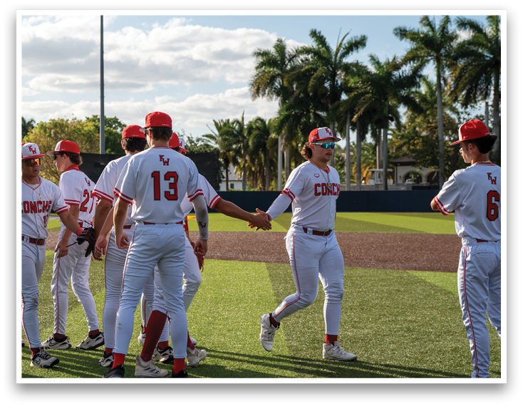 A group of baseball players wearing red and white uniforms. Description generated by AI