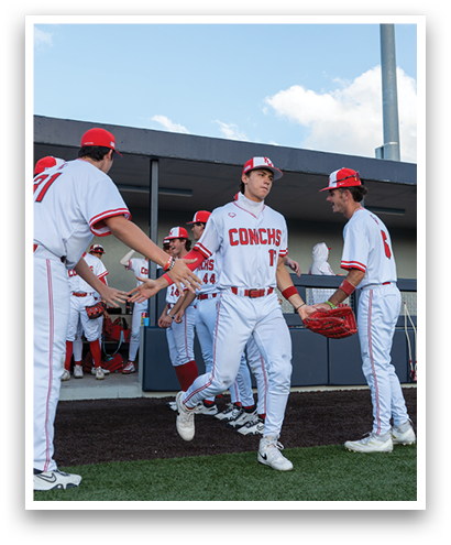A group of baseball players wearing red and white uniforms. Description generated by AI